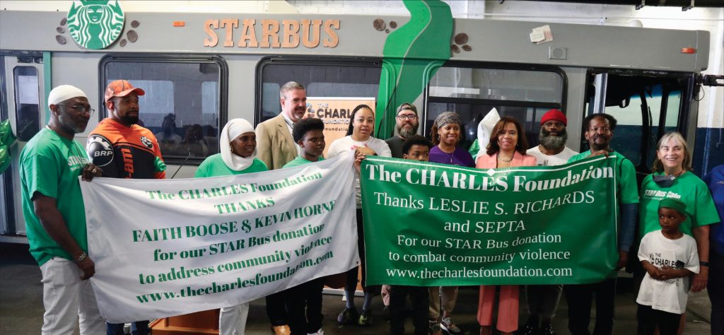 professionals and community volunteers hold banners in front of bus