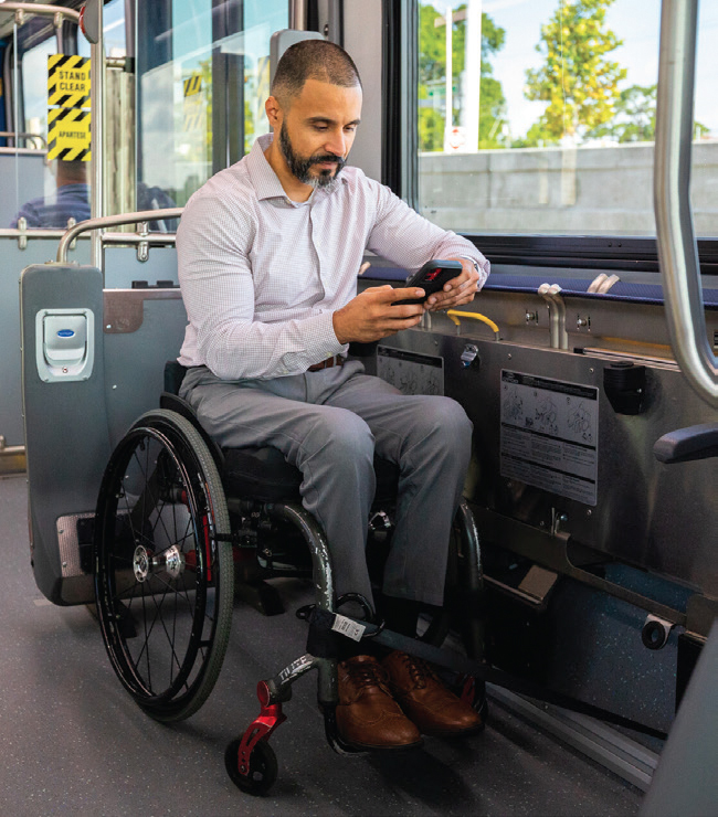 man in wheelchair checks phone on bus