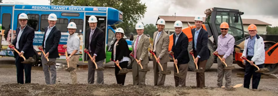 executives break ground in front of bus at construction site